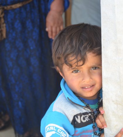 A small refugee looks towards the camera